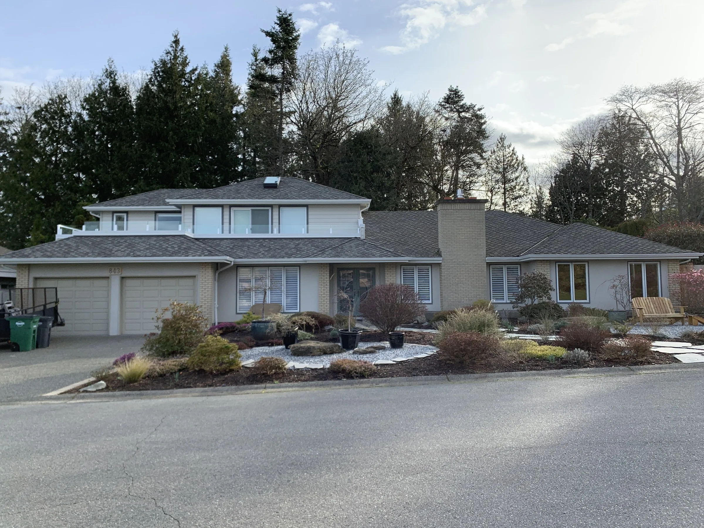 Large two-storey home with brick base and a glass-railed upper deck addition